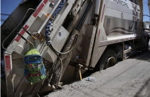 Se atora camión de basura por socavón